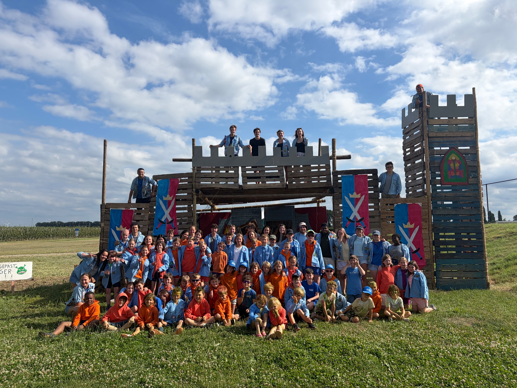 De volledige groep van KSA Waregem op kamp, voor een zelfgebouwde constructie.
